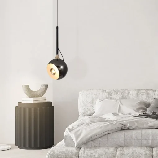 Modernne must energiatsäästlik LED ripplamp elutoa või magamistoa interjööris, ripub üle minimalistliku öökapi, millel on hallid betoonist dekoratiivesemed. Taustal on elegantne hall voodi.