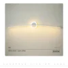 Moodne disain LED seinalamp, kumer valge valgusriba, paigaldatud minimalistlikule heledale seinale, kiirgab sooja valget valgust.