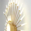 Stiilne moodne ja nutikas dimmertatav LED laelühter kuldsetes toonides, millel on säravad, mitmesuurused valgustid, moodustades elegantse päikesekiirte disaini valgel taustal.