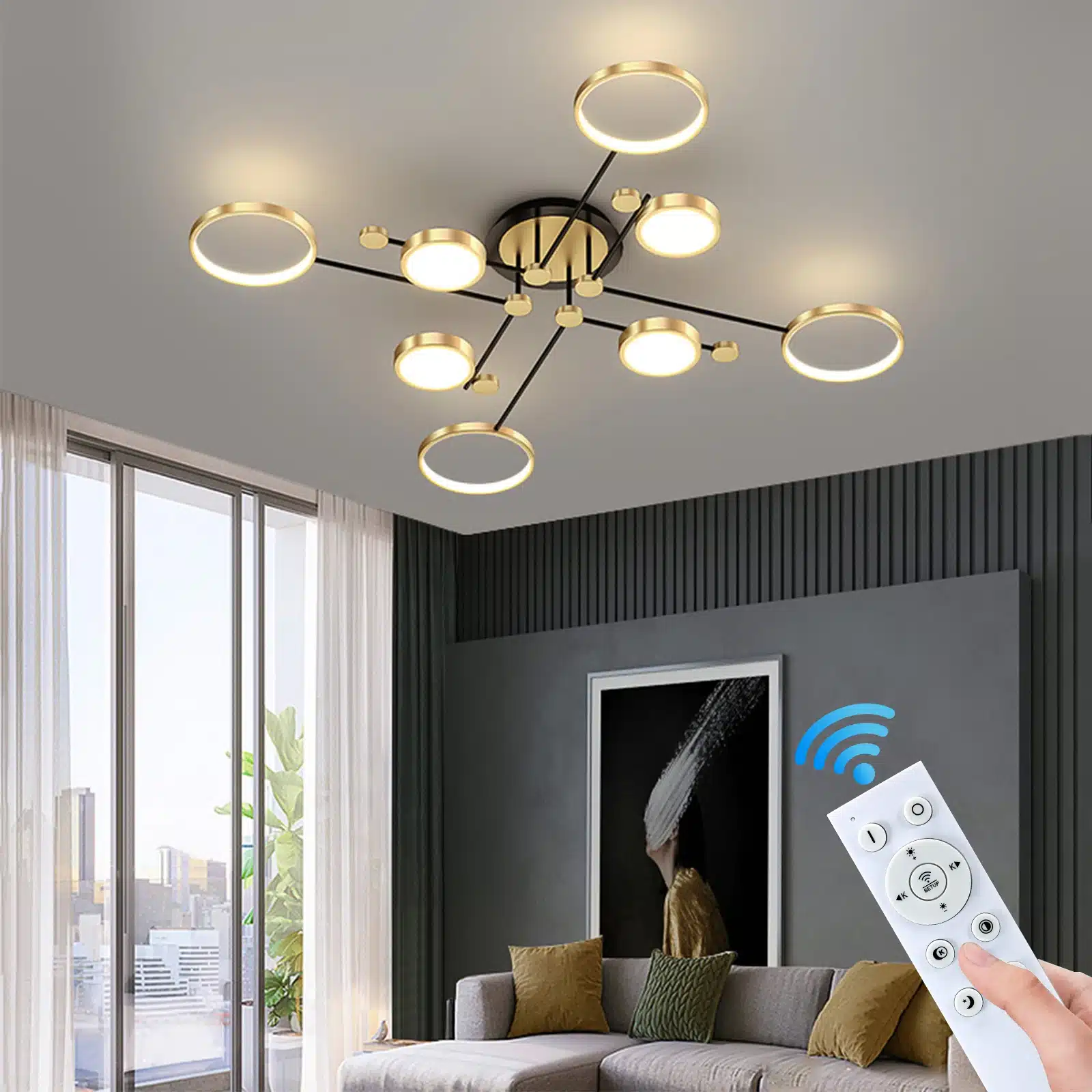 Kaasaegne tuba, mille laes on luksuslik puldiga LED laelamp, mille kuldsed ringid ja mustad ühendused loovad elegantse valguse. Esiplaanil on juhtpult, mis lisab mugavust toote kasutamisele. Taustal hele tapeet ja suured aknad.