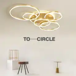 Kaasaegne stiilne LED laelamp kuldsete ringidega helendamas avaras elutoas minimalistliku mööbli taustal. Stiilne LED laelamp magamistuppa või elutuppa täiendab ruumi elegantselt.