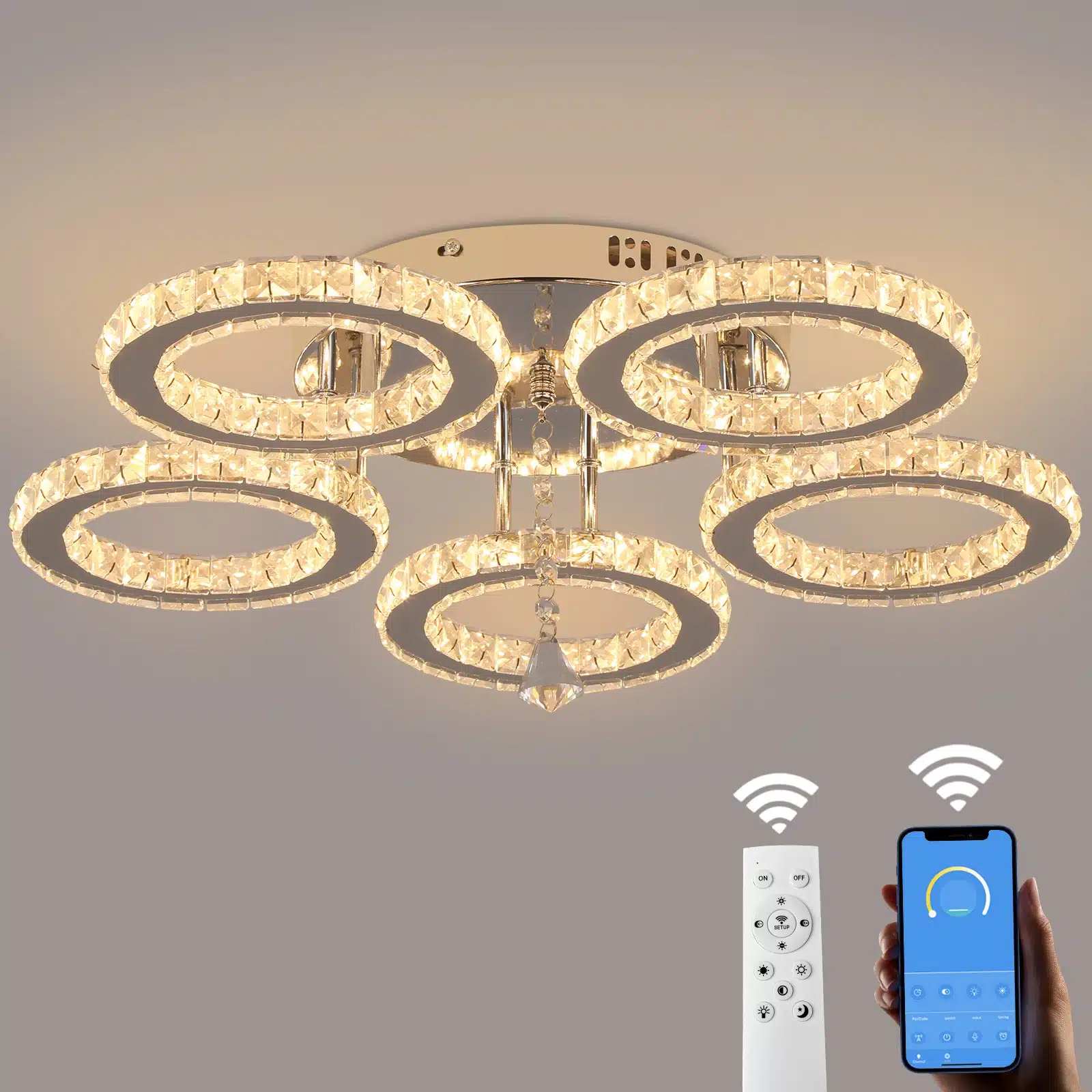 Elegantne kristallidega kaunistatud laelamp, mis koosneb kuldsetest LED-valgustitega rõngastest ja mille juhtimine toimub äpi või puldi abil. Lamp on paigaldatud stiilsele metallalusele heledal taustal.