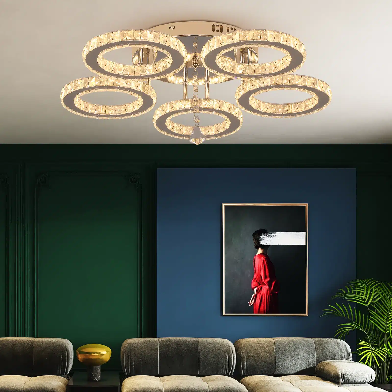 Stiilne äpi või puldiga juhitav kristallidega laelamp, mis ripub elegantses elutoas sinise seina taustal. Lamp koosneb mitmest helendavast rõngast, mis loovad sooja ja luksusliku atmosfääri.