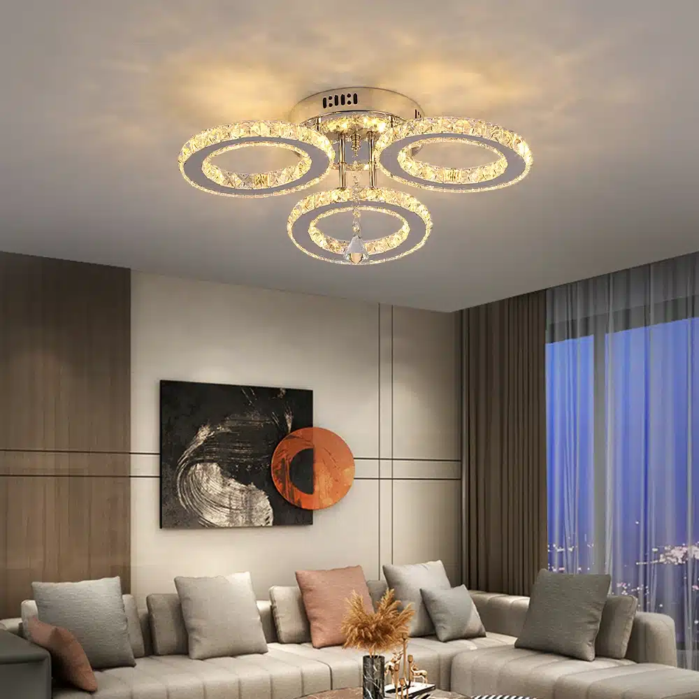 Moodne elutuba, mille laes ripub äpi või puldiga juhitav kristalllidega laelamp. Lamp särab soe valgus metallist ja kristallidest ringides, lisades ruumile luksusliku ja elegantse ilme.