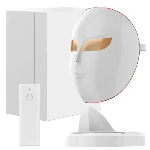 Efektiivne valgusteraapia mask näonaha pingutamiseks ja noorendamiseks | E-pood Tootemaailm Valge efektiivne valgusteraapia mask näonaha pingutamiseks ja noorendamiseks koos juhtimisseadmega. Maskil on kuldsed silmaavad ja see asub elegantse aluse peal minimalistliku taustaga.