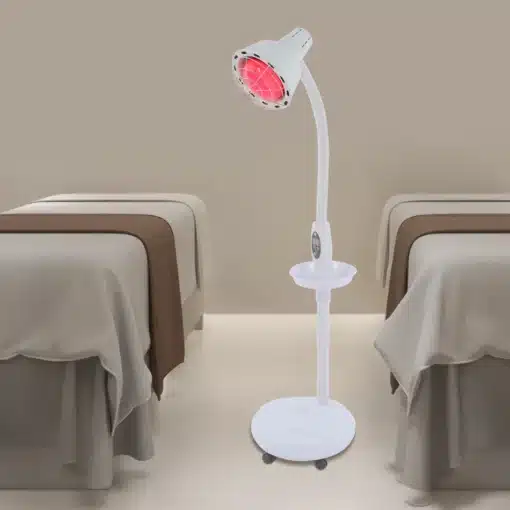 Võimas infrapuna füsioteraapia lamp valu leevendamiseks | E-pood Tootemaailm Modernne valge infrapuna füsioteraapia lamp punase valgusega, asetsev mugavas terviseruumis kahe voodi vahel beeži tausta ees.