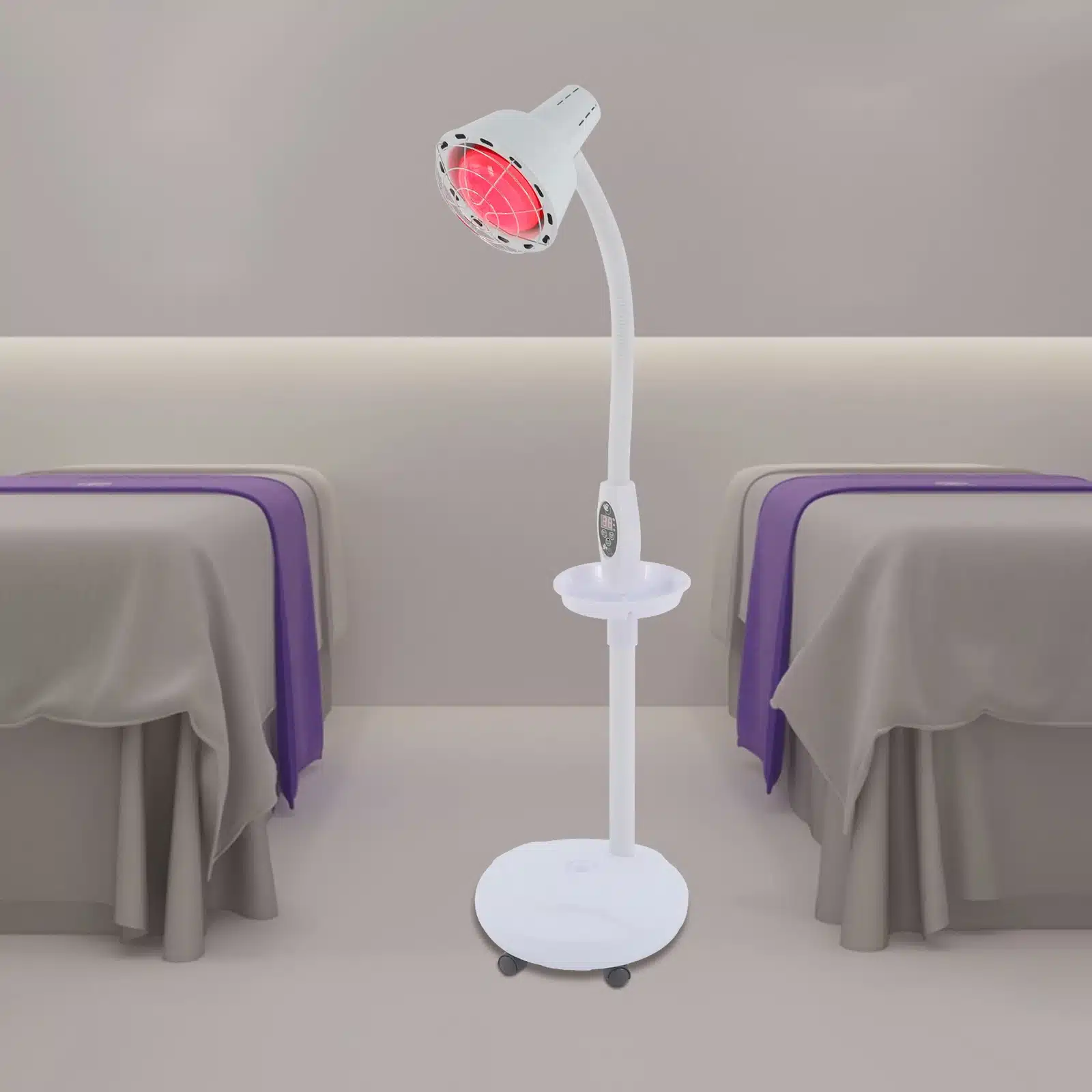 Valge võimas infrapuna füsioteraapia lamp punase valgusega, seisab teraapiaruumi keskel, taustal kaks kaetud massaažilauda hallides ja lillades toonides.