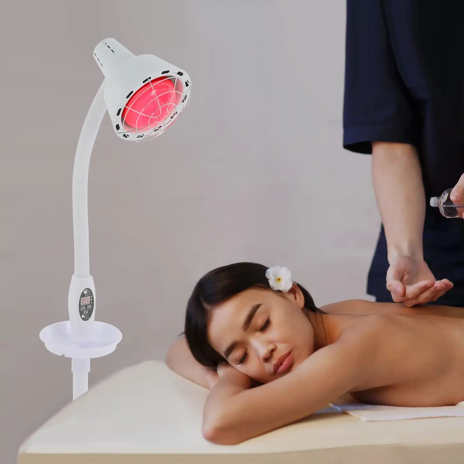 Naine lebab massaažilaual, samal ajal kui valge võimas infrapuna füsioteraapia lamp kiirgab temale soojust, aidates leevendada kehalisi pingeid kaasaegses teraapiakeskkonnas.