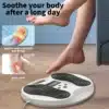 Eriti efektiivne EMS jalamassaažiseade, kahe juhtnupuga, valge ja musta värvi plast, jalgadega diivanist väljasirutatud naine, puitpõrandal.