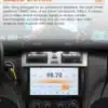 Must Mercedes-Benz W203 W209 multimeedia autoraadio, mille 9-tolline ekraan näitab raadio sagedust 98.70 FM. Raadiol on mitmesuguseid juhtimisnuppe ja autos on musta nahast interjöör. Taustal on näha uduseid valgussähvatusi.