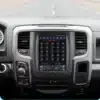 Dodge RAM auto esipaneel, millel on CarPlay multimeediakeskus. Must värviline puuteekraan, ümbritsetud mugavate juhtnuppudega, asetatud hõbedase ja musta armatuuri keskele. Taustal nähtav tee toob esile multimeediakeskuse kasutusmugavuse sõidu ajal.