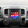 Dodge RAM CarPlay multimeediakeskus sõiduki esipaneelil, kuhu on integreeritud kõrge resolutsiooniga ekraan, mis kuvab erinevaid rakendusi ja ikoonid värvilisel taustal. Multimeediakeskuse all on auto juhtpaneel ja küljel nupud kliimaseadme jaoks. Lisaks kuvatakse CarPlay ja Android Auto logo koos märksõnadega Wireless ja Wired.
