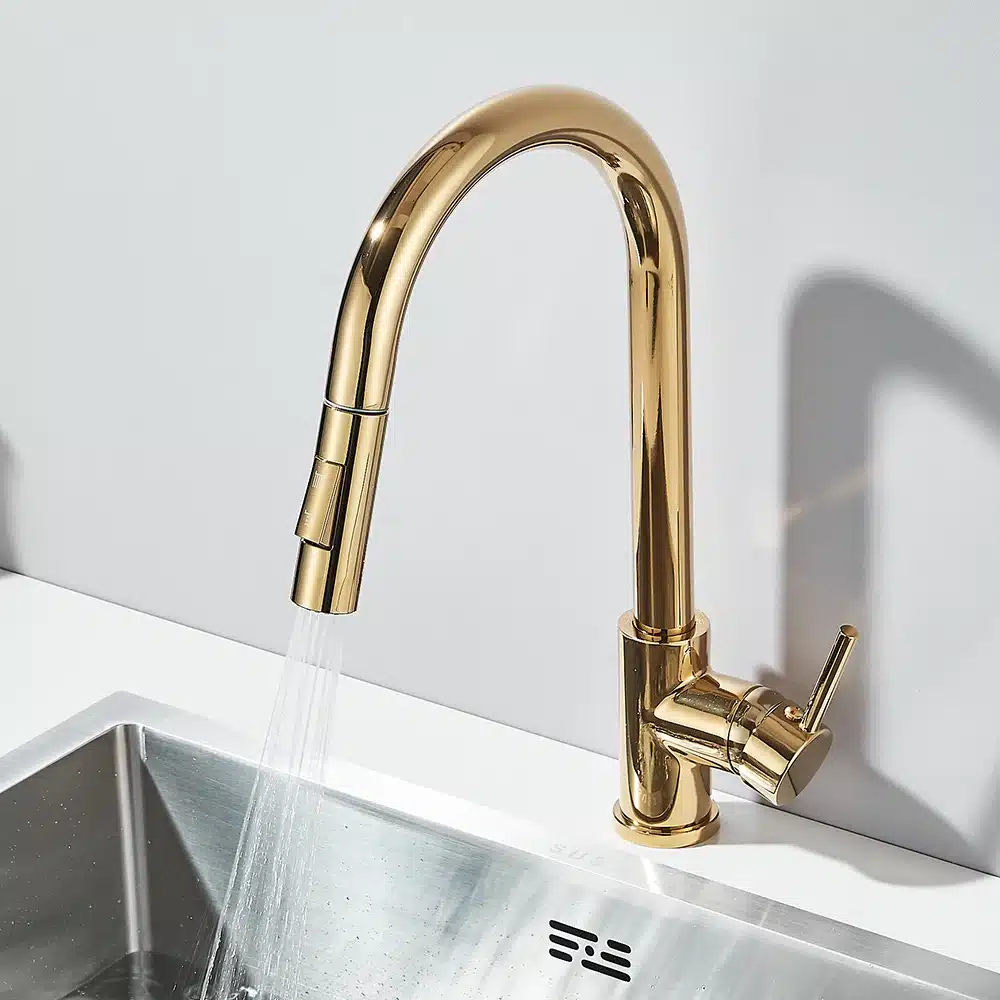 Köögisegisti kahe voolurežiimiga ja segamisfunktsiooniga kuldses toonis, paigaldatud kaasaegsele köögivalamule, taustal valge sein.