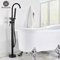 Põrandale paigaldatav vannisegisti käsidušiga, must metall, kaasaegselt stiilses vannitoas, mille taustal on aknad ja isikupärane vaba seisev valge vann.