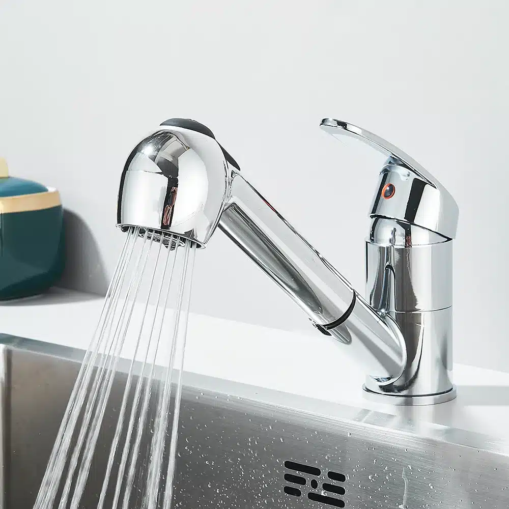 Kroomitud köögisegisti, ühekohaline, hõbedase läikega, veejuga välja laskmas roostevabast terasest kraanikausis, minimalistliku taustaga.