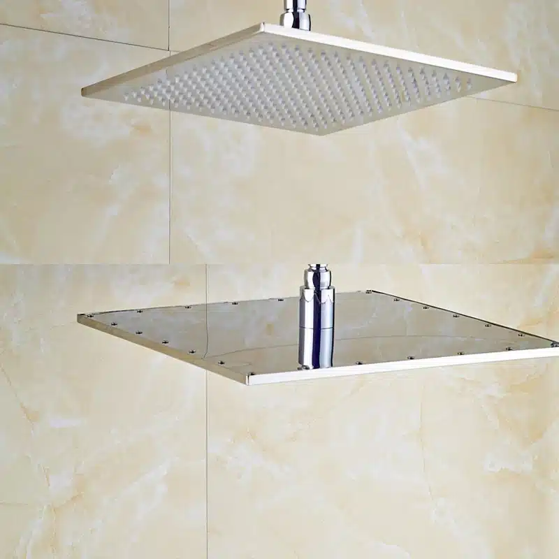 Messingist ruudukujuline vihmadušš LED-valgusega, mis on paigaldatud heledale plaaditud seinale. Läikiv viimistlus peegeldab valgust, luues luksusliku ilme.