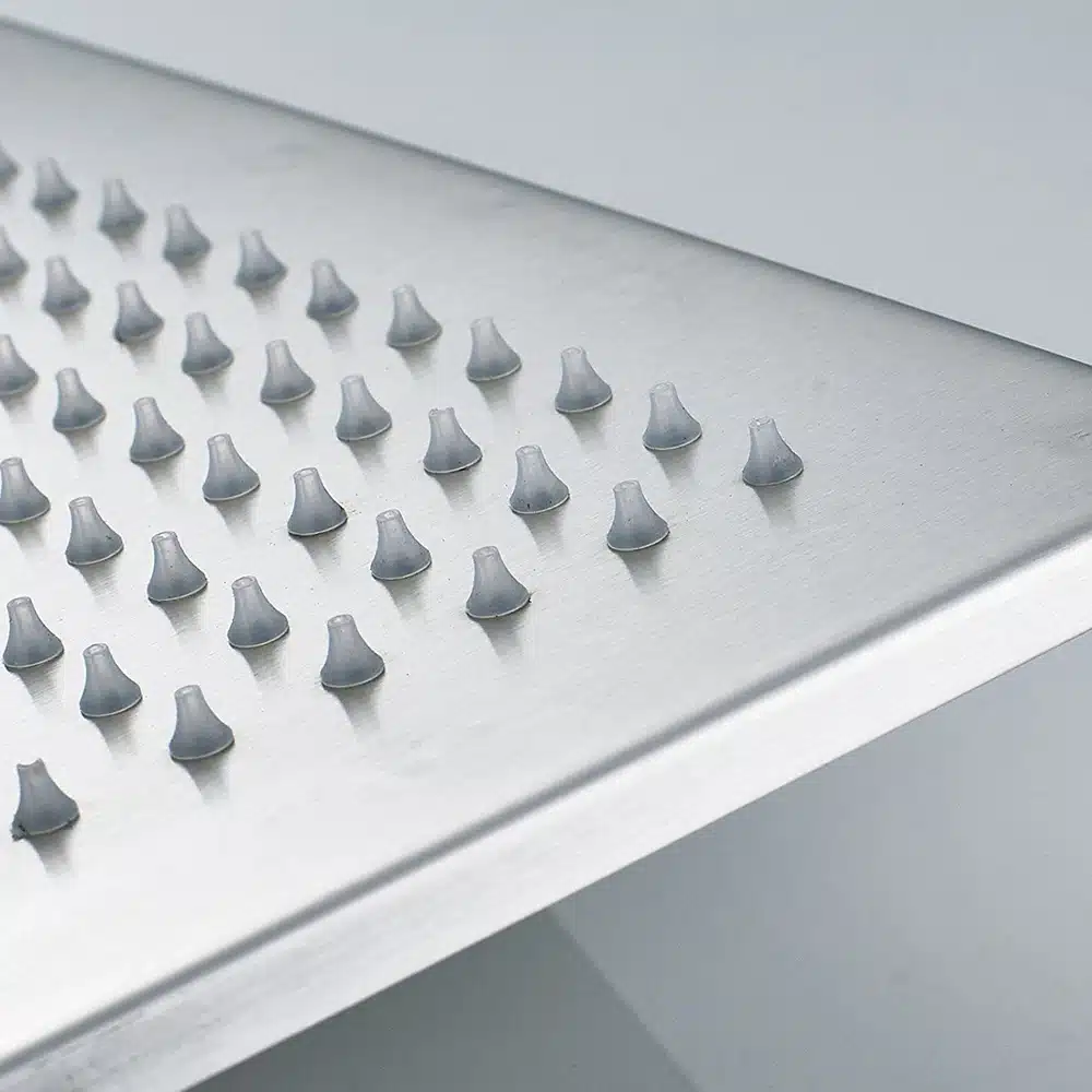 Lähivõte ruudukujulisest messingist vihmaduši peast, millel on LED-valgustusega kroomitud pind. Nähtaval on hallid veepihustuse düüsid, mis jaotuvad ühtlaselt üle dušipea pinna.