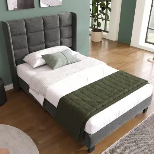 Üheinimesevoodi pehme peatsiga, hall linakangas 90x200 cm | E-pood Tootemaailm Üheinimesevoodi pehme peatsiga, hall linakangas 90x200 cm, asetatud heledale puidust põrandale valgusküllases ruumis, taustal roheline sein ja aknad.