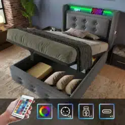 Polsterdatud üheinimesevoodi LED-peatsi ja USB-C laadijaga. Hall kangas, nuppudega muster, tõstetav madrats ladustamise võimalusega, meeldiva valgusefekti ja laadimistoe. Puitpõrandal heledas magamistoas, lisatud kaugjuhtimispult.