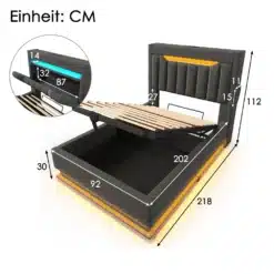 Hall linane üheinimesevoodi koos panipaiga ja USB-laadijaga, voodi kõrval on mõõtmed näidatud sentimeetrites. Voodi pealis on üles tõstetud, paljastades all oleva mahuka panipaiga. Tausta eristab hele valgusvooderdus, mis lisab voodile modernse hõngu.