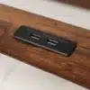 Üheinimesevoodi USB pesaga ja LED valgustusega 90x200 | E-pood Tootemaailm Pilt näitab üheinimesevoodi 90x200 puitpinda, kuhu on integreeritud kaks USB pesa, mis on musta plastist raamides. Puidust pind on lakitud ja tekstuurne, sobib kaasaegse magamistoamööbli stiiliga.