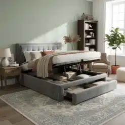 Kaheinimesevoodi panipaikade ja sahtlitega, hall 140x200 toas puidust põrandal, pehme peats ja avatud panipaik koos sahtlitega. Taustal pastelne sein, raamatukapp ja tugitool.