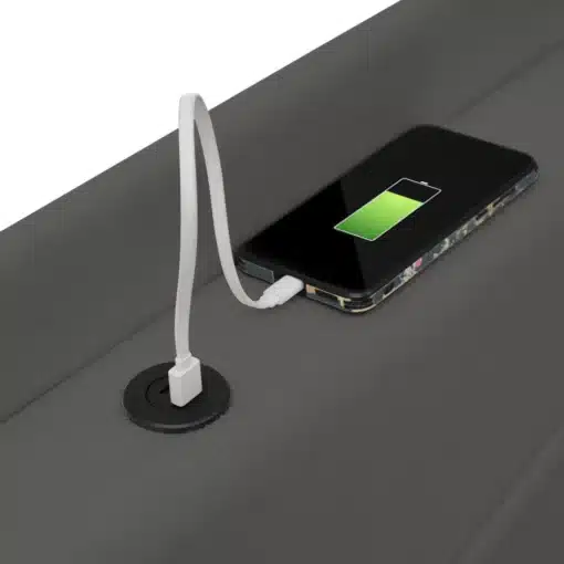 Üheinimese voodis on USB Type-C laadija, mis laeb nutitelefoni, mis asub kvaliteetsel hallil madratsil.