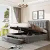 Kaheinimesevoodi panipaikade ja sahtlitega, hall 140x200, elegantse kangapealisega tõstetud madratsi ja avatud sahtlitega modernselt kujundatud magamistoas, päevavalguses akna kõrval.