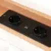 Stiilne voodi USB-C laadijaga ja panipaigaga 160x200 tihedas puidust raamistikus, millele on integreeritud must laadimispaneel, sisaldades USB-C porti ja kahte pistikupesa mugavaks seadmete laadimiseks.