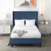 Polsterdatud voodi sinine 90x200 cm koos vedrumadratsi ja valgete voodipesudega, paiknedes modernses magamistoas, mida täiendavad öökapid ja seinal kunstiteos.