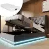 Pilt näitab elegantset halli magamistoa voodit suurusega 90×200, millel on avatud pesukast. Voodil on peats, taustal on näha puidust sein ning pehme hall polster. USB- ja LED-valgustused loovad moodsa atmosfääri.