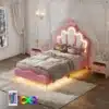 Tüdrukute voodi LED valgustusega roosa 90x200 cm, mille peatsis on kroonimotiiv ja kerge valgustus. Voodeid ümbritsevad pehmed voodipesud ja puidust seinad, luues hubase lastetoa atmosfääri.