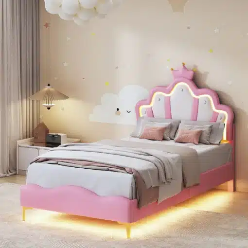 Roosa tüdrukute voodi LED valgustusega, mõõtmetega 90x200 cm, eristub kaunist krooni motiiviga peatsil, lisades magamistoale printsessilikku hõngu. Taustal pilvemustriga hele sein, valgusallikad loovad pehme atmosfääri.