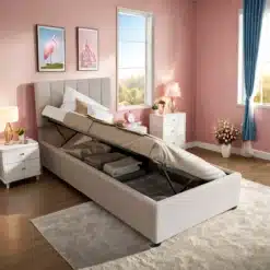Beež linane üheinimese voodi suurusega 90x200 cm, mille peatsis on panipaik avatud asendis. Voodi on asetatud roosas magamistoas, mida kaunistavad elegantsed sisustuselemendid nagu valged öökapid ja sinised kardinad.