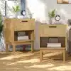 Kaks boho stiilis öökappi rotangdetaile ja puidust sahtlitega, paiknevad valgusküllases ruumis puitpõrandal. Sahtlite peal on stiilsed kellad ja taimed dekoratsioonina.