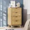Kummut nelja sahtliga tammepuidu toonis, mille ristkülikukujulised sahtlid paiknevad stiilses magamistoas heleda vaiba ja sinise seina taustal. Kummuti peale asetatud dekoratsioonid lisavad ruumile elegantsi.
