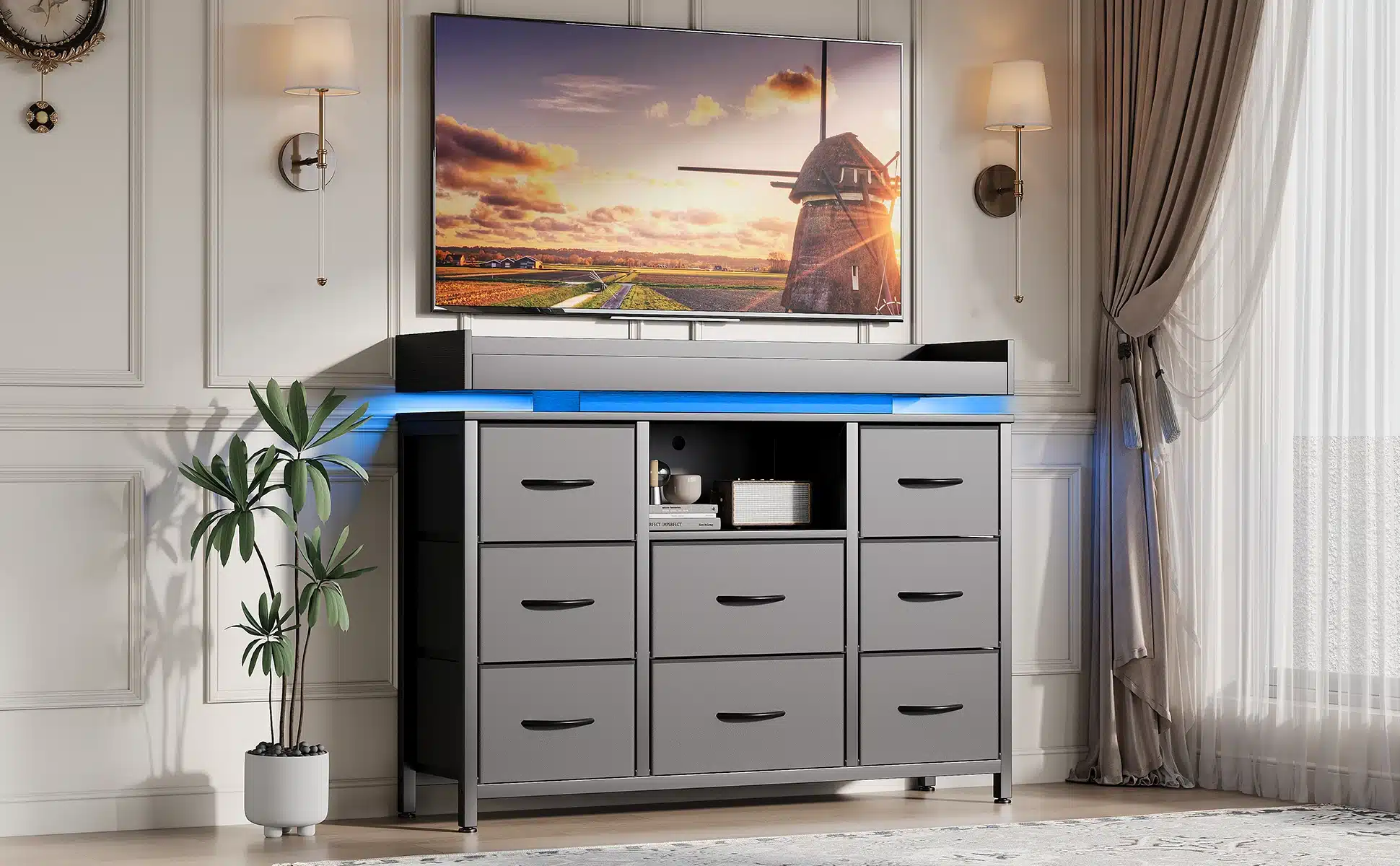 Elegantses elutoas seisab hall kummut, millel on LED valgustus, kaheksa sahtlit ja USB laadimisport. Kummuti peal asub laud, millel on dekoratiivesemed. Seinad on heledad ja aknal rippuvad poolläbipaistvad kardinad.