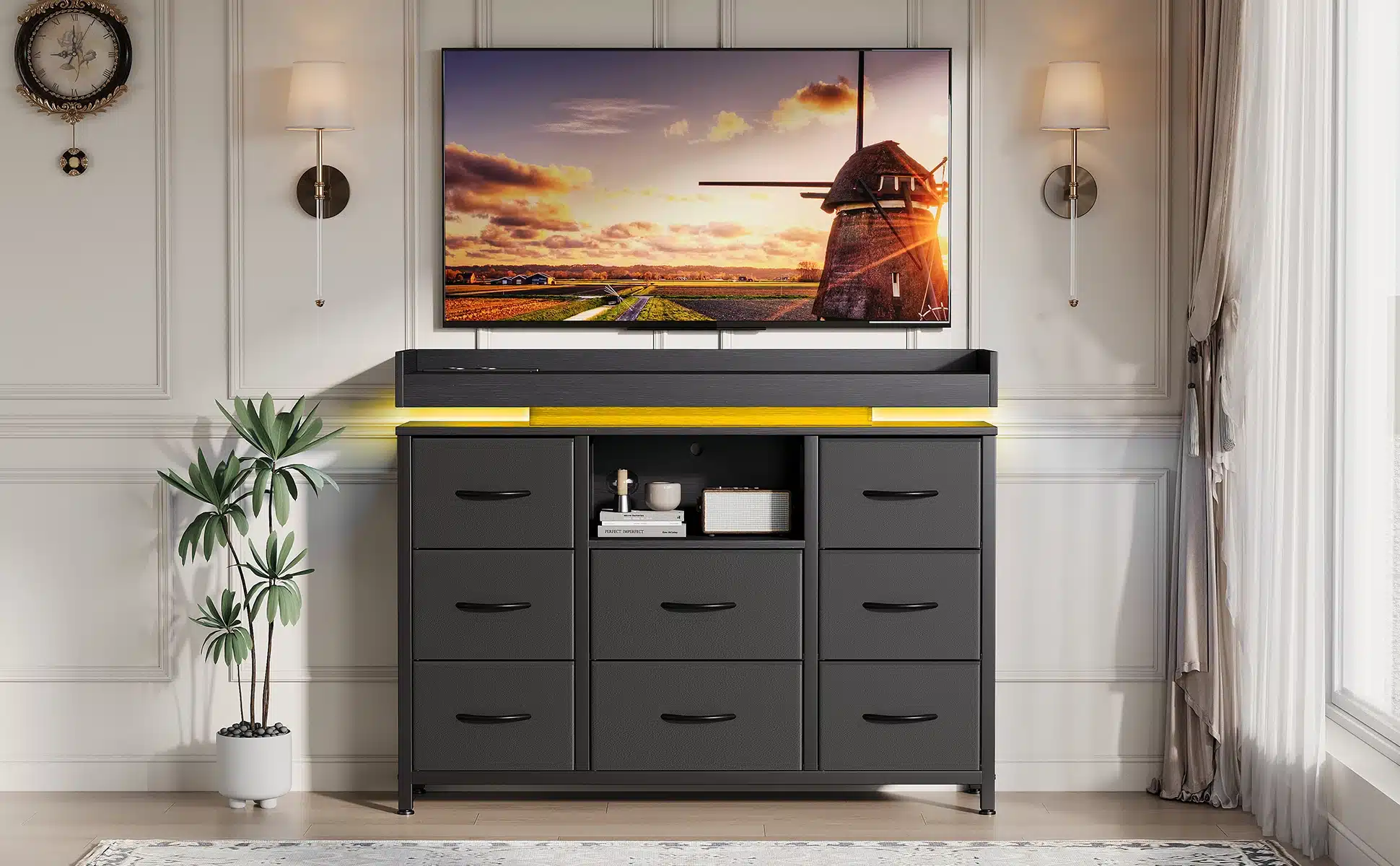 Elegantses interjööris must kummut LED valgustusega, 8 sahtlit ja USB laadimisport, mille peal on kaasaegne televiisor; taustal hele seinapaneel ja aknast langev valgus