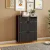 Must kingakapp kahe sahtli ja nelja sektsiooniga, mõõtmetega 80x24x110 cm. Kapp on paigutatud stiilsesse elutuppa, ümbritsetud dekoratiivsete piltide ja toataimedega. Kapil olevad kuldsed käepidemed ja peene tekstuuriga pinnaviimistlus lisavad elegantsi.
