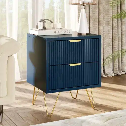 Tumesinine öökapp kahe sahtliga ja metalljalgadel, mille peal on raamatud ja valge lamp. Öökapp asub valgusküllases ruumis heledal puitpõrandal, taustal nähtavad kardinad ja toa dekoratsioonid.