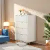 Valge, modernne kummut nelja sahtliga, mõõdud 91x34x60 cm, asetseb elegantses elutoas, millel on sinine diivan ja rohelised taimed, kuldsed käepidemed lisavad luksuslikkust.