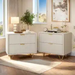 Kahe valge öökapi komplekt, igaühel kaks sahtlit ja kuldsed metalljalad, paiknevad elegantse aknaga valgustatud ruumis, millel on puidust põrand ja heledad kardinad.