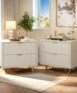 Kahe valge öökapi komplekt, igaühel kaks sahtlit ja kuldsed metalljalad, paiknevad elegantse aknaga valgustatud ruumis, millel on puidust põrand ja heledad kardinad.