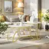 Elegantsed ümarad diivanilauad marmori välimusega, millel on kuldsed metallraamid. Need lauad seisavad maitsekalt valgel vaibal, lisades elutoa sisustusele luksuslikku puudutust. Võluvad interjöörivõtted koos lillede ja diivaniga loovad rahuliku atmosfääri.