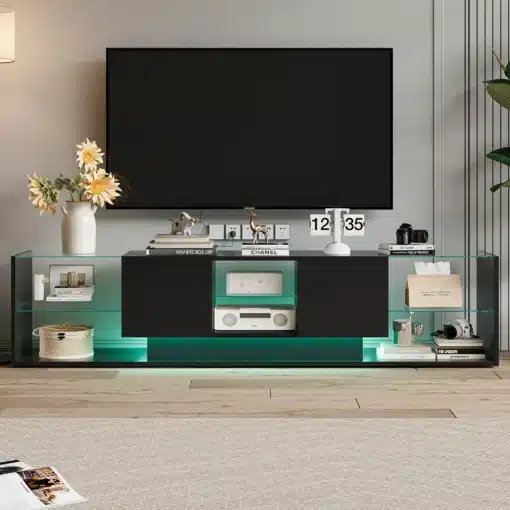 Moodne TV-alus LED-valgustusega ja kahe sahtliga, mõõtmetega 200x35x45 cm. Alus on musta värvi, klaasist külgriiulitega ja integreeritud LED-valgustusega, mis lisab elutuppa stiili ja funktsionaalsust. Alusel on paar dekoratiivset elementi, nagu lillevaas ja erinevad raamatud, mis rõhutavad selle elegantsust.