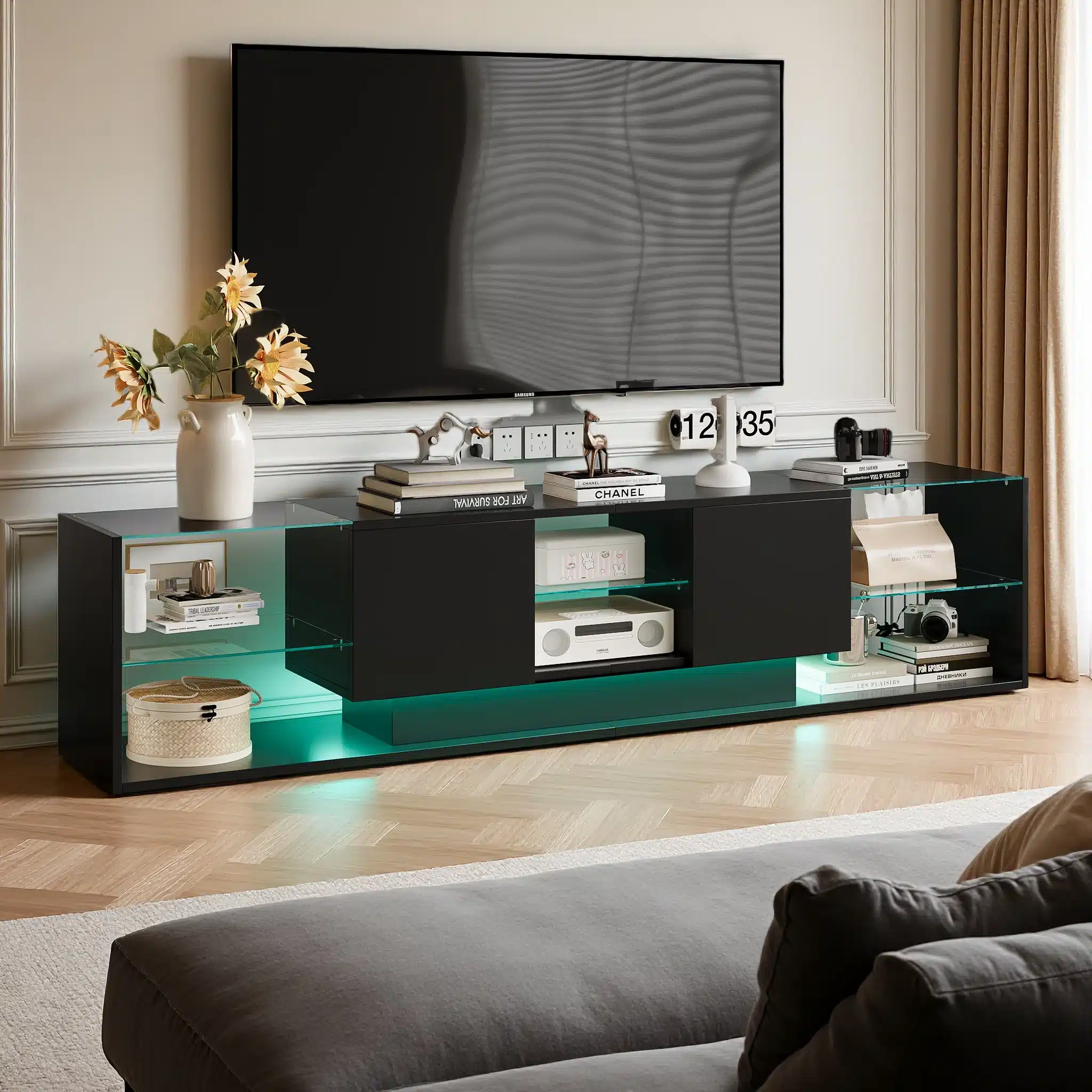 Elegantne must TV-alus koos LED-valgustuse ja kahe sahtliga, mõõtmetega 200x35x45 cm, asub elutoa valgusküllasel puitpõrandal. Sellel on kaasaegsed riiulid ja dekoratiivsed esemed, taustal näha taupe kardinad.