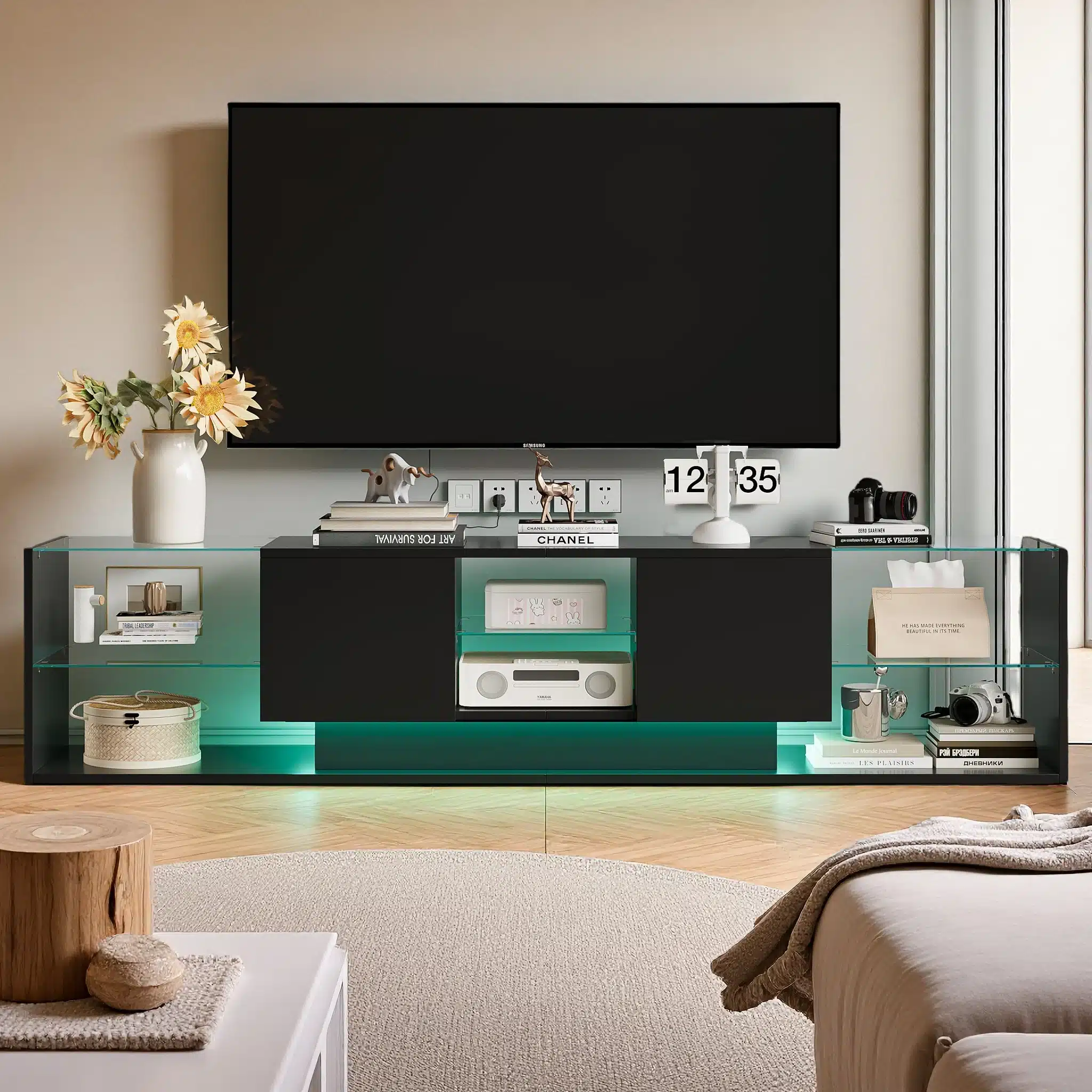 Stiilne TV-alus LED-valgustusega ja kahe sahtliga elutoas, mõõtmed 200x35x45 cm. Musta mööbli peal valge kaunistustega vaas lilledega ning kaasaegne meelelahutustehnika.
