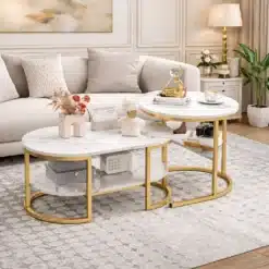 Diivanilauad marmorefektiga, ümarad, komplekt 2 tk, beežil vaibal elegantse diivani ees, koos kuldsete jalgade ja dekoratiivsete esemetega, elutoa mugava ja stiilse interjöörina.