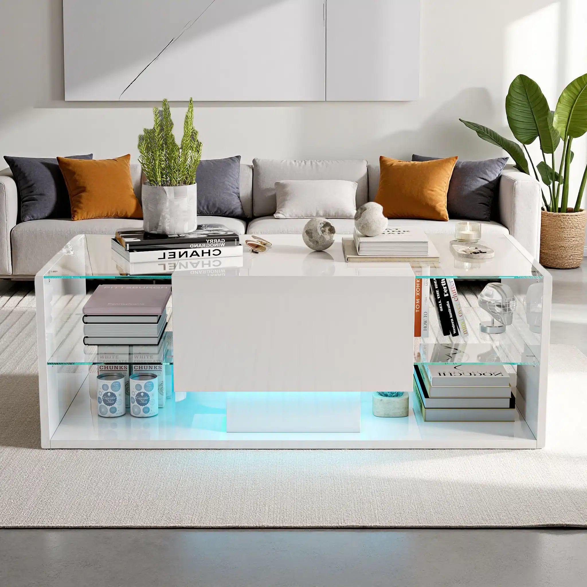 Diivanilaud LED valgustusega, läikiv lakk ja sahtlid, suurusega 100x50x35 cm, asub moodsa elutoa heledal vaibal, ümbritsetud hubase sisustusega, kus on näha diivan ja toataimed.