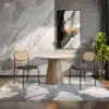 Kaks polsterdatud söögitoa tooli rotangseljatugedega, asetsevad kiviimitatsiooniga vaibal, taustal marmorsein ja maali. Minimalistlik sisekujundus ja elegantne mööbel loovad kaasaegse ilme.